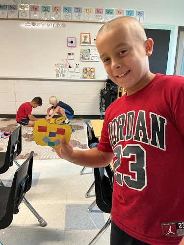 School age boy smiling with his end product