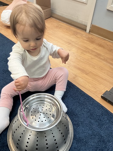 child tapping on a bowl listening to the sounds it makes