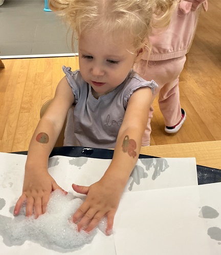 Toddler squishing bubbles with her hands