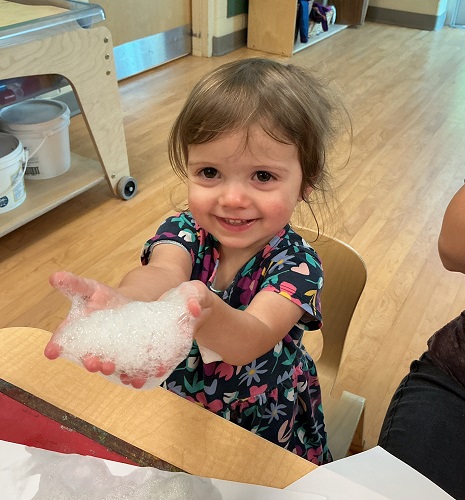 Toddler exploring with bubbles on her hands