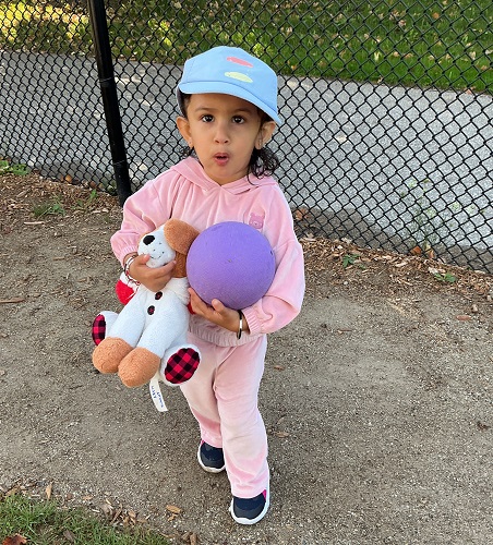 Toddler child exploring with a purple ball outside
