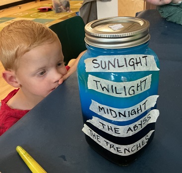 Child looking at a jar that has different layers of blue in it