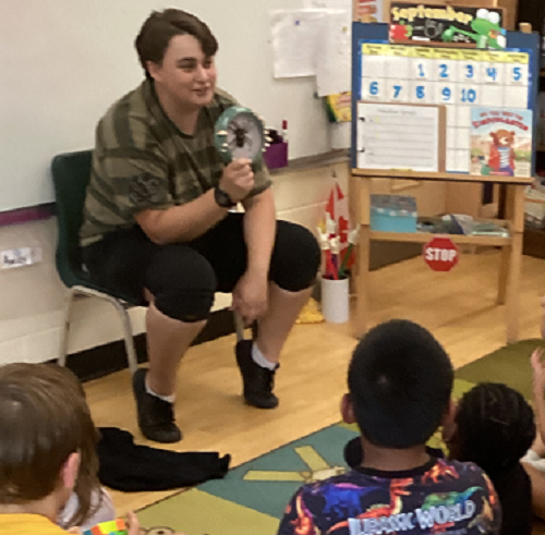 Educator showing tarantula skin to children sitting on the carpet