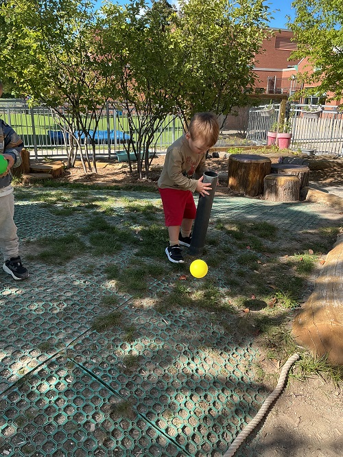 a child seen looking down a pipe to find the ball